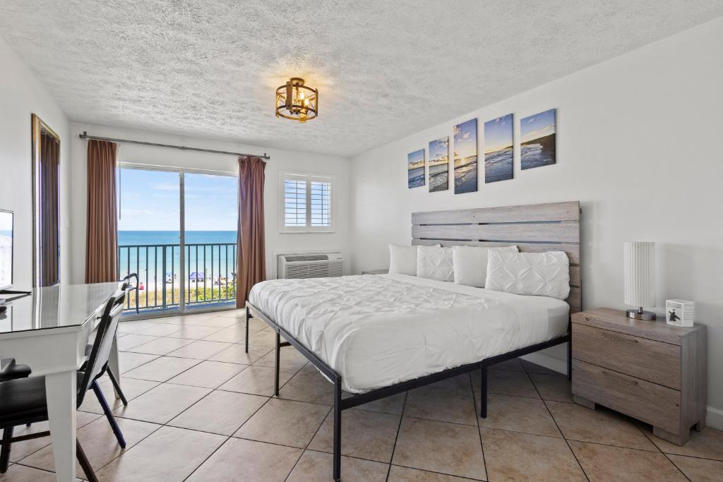 a bedroom with a bed and a table and a desk at Oceanfront Inn Room #25- Ocean View Balcony King Bed in Fort Pierce