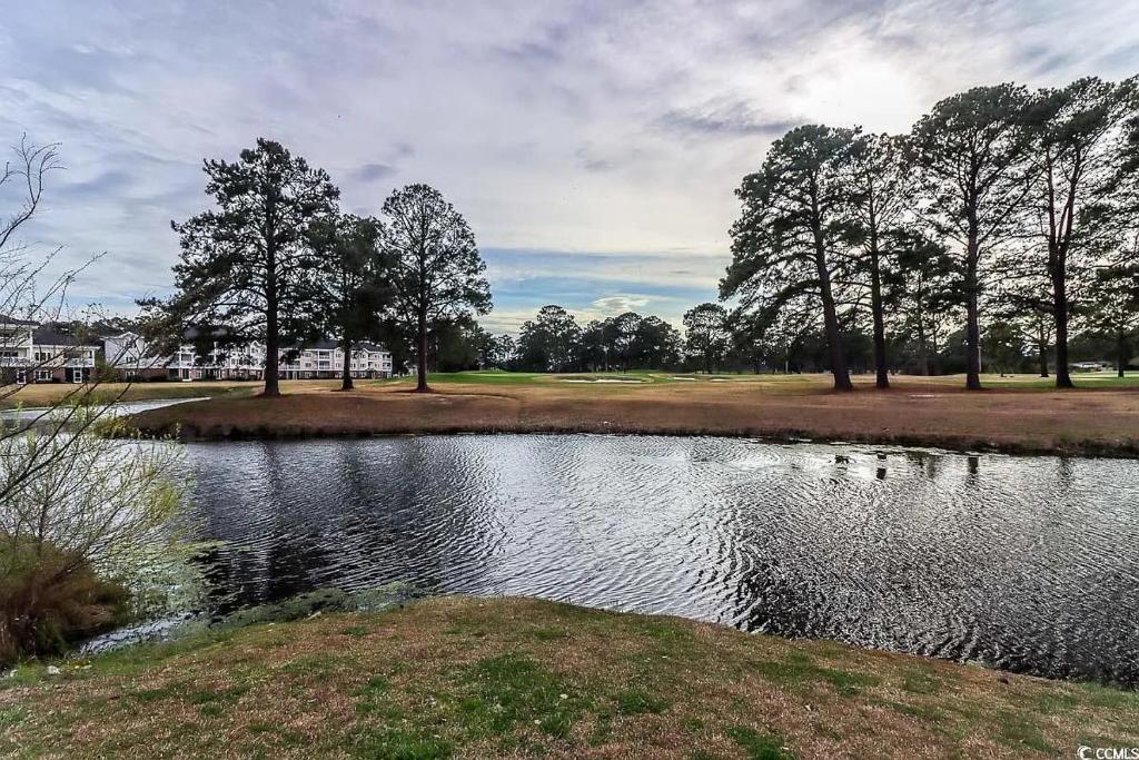 einen Teich in einem Park mit Bäumen im Hintergrund in der Unterkunft Beautiful 1500 s f 3 Bd - 2 Ba condo overlooking stream and golf course in Myrtle Beach