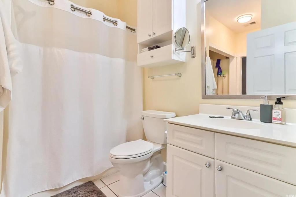 ein Badezimmer mit Toilette, Waschbecken und Spiegel in der Unterkunft Beautiful 1500 s f 3 Bd - 2 Ba condo overlooking stream and golf course in Myrtle Beach