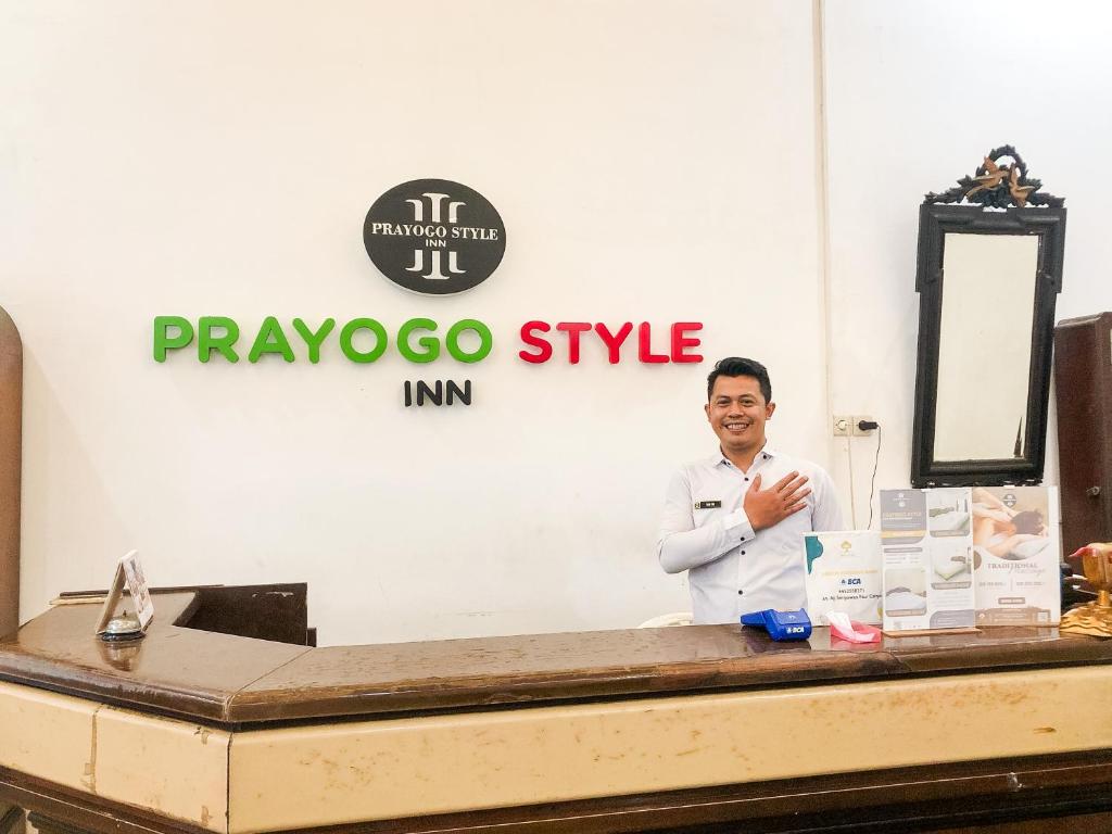 a man standing at a reception desk in front of a sign at Prayogo Style Inn Prawirotaman in Yogyakarta