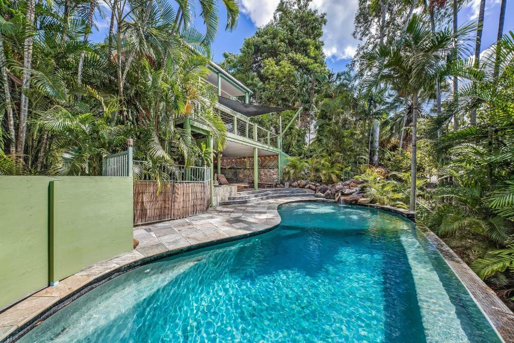 a swimming pool in front of a house with trees at Treetop Paradise Retreat with Pool in Cannonvale