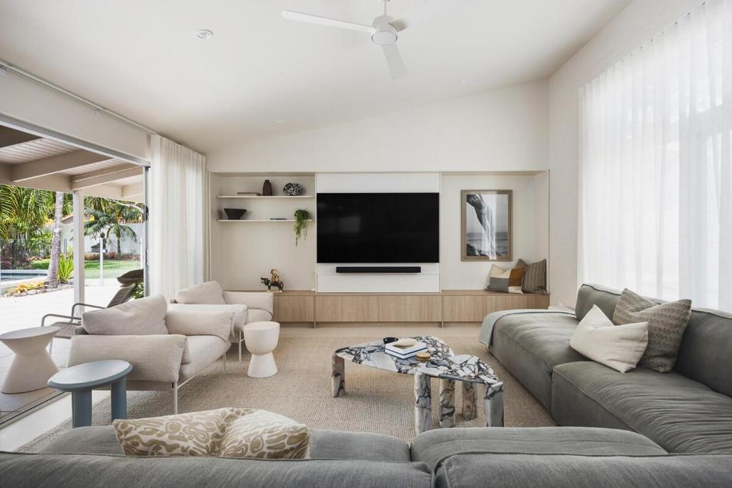 Una sala de estar con un sofá y un televisor de pantalla plana. en Coastal Haven on Witta, en Noosa Heads