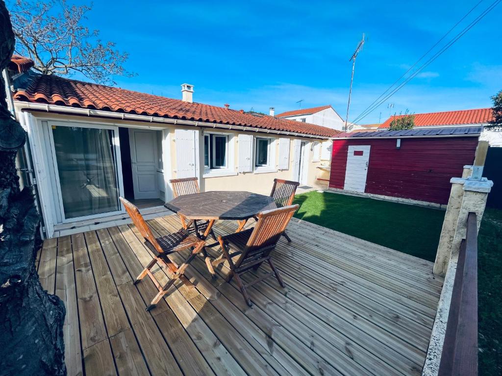 une terrasse en bois avec une table et des chaises dessus dans l'établissement La ptite maison de Royan pour 4 personnes avec jardin, à Royan