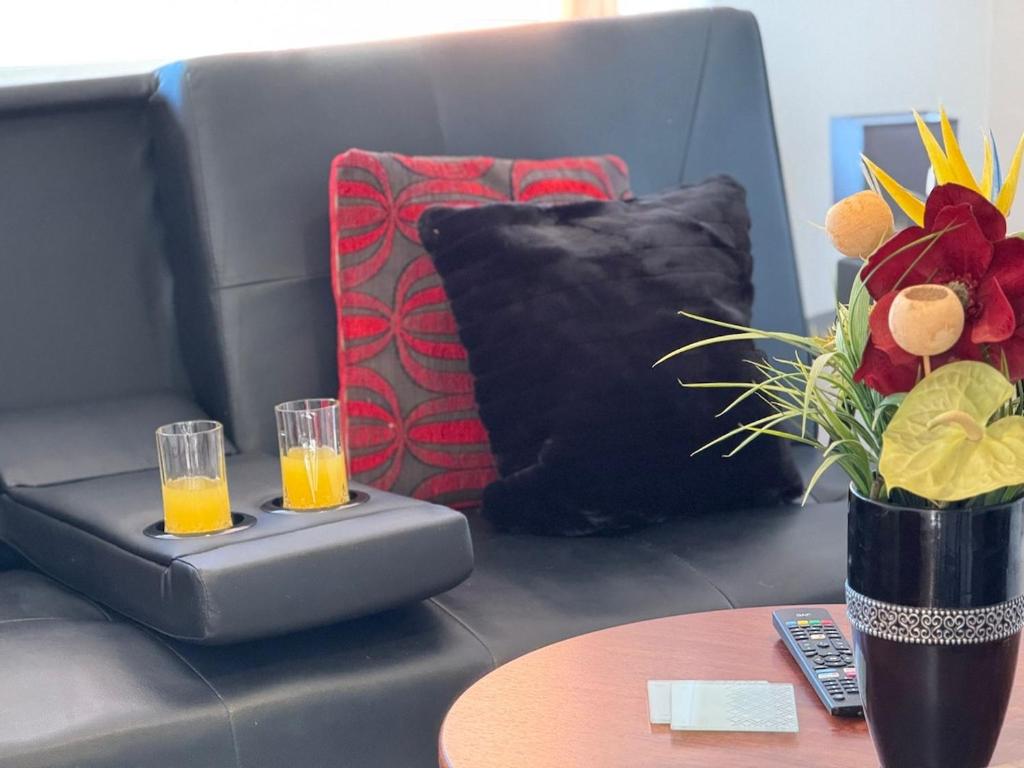 a couch with two glasses of orange juice on a table at PRIME LOCATION Luton home - FREE PARKING in Luton
