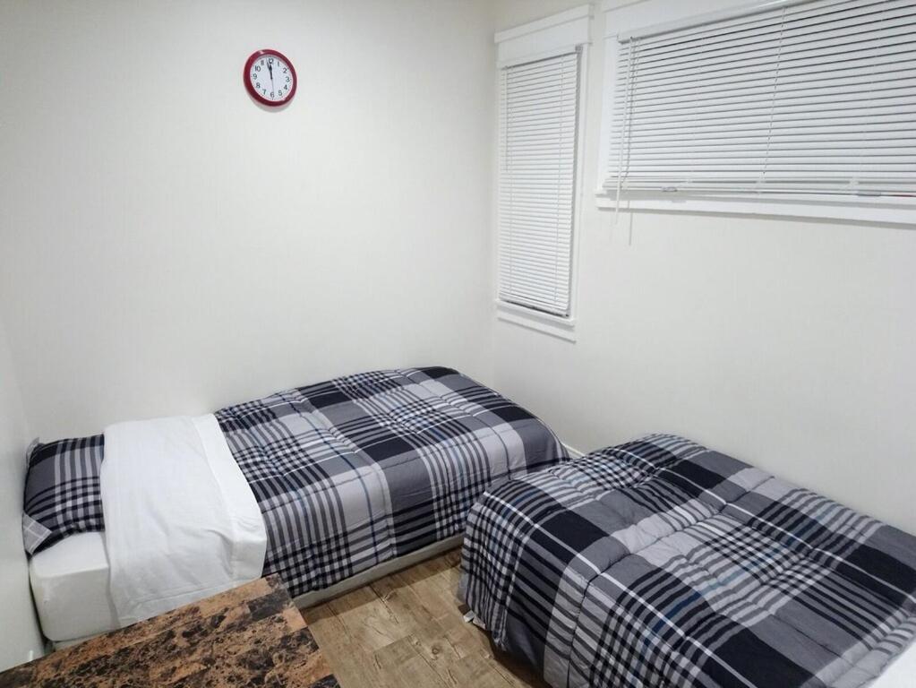 a bedroom with two beds and a clock on the wall at Vacation Unit is Available for Business and Family Trip in Long Beach