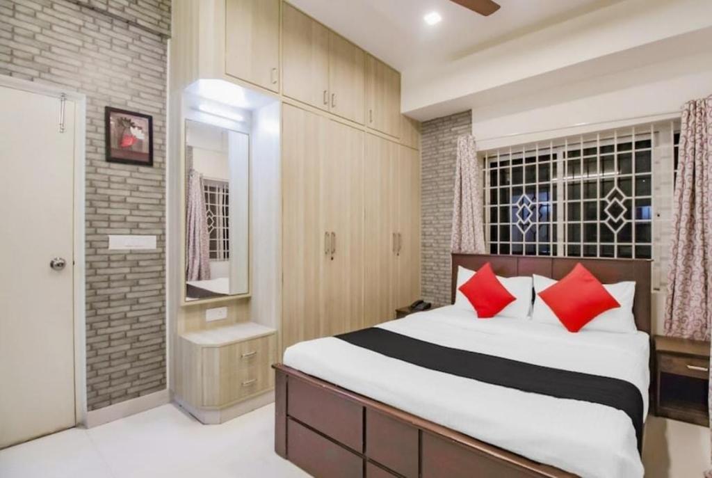 a bedroom with a large bed with red pillows at SLN Suites, Near Baptist Hospital, Hebbala in Bengaluru