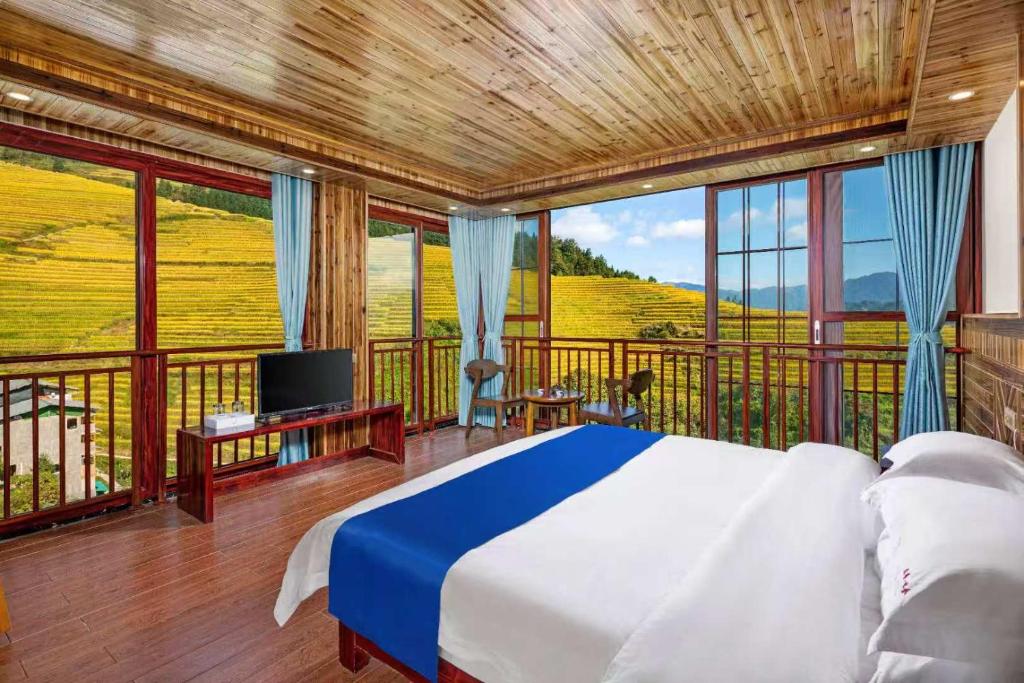 a bedroom with a bed and a balcony with a tv at Longji Forest Lodge--Terraced landscape from the room, Pick-up and drop-off service from Ping'an Village Parking Lot, Sunrise& Sunset in Heping