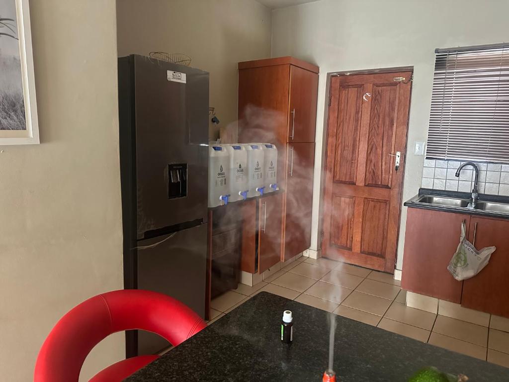 a kitchen with a stainless steel refrigerator and a red chair at Kwa Ndosi in Polokwane