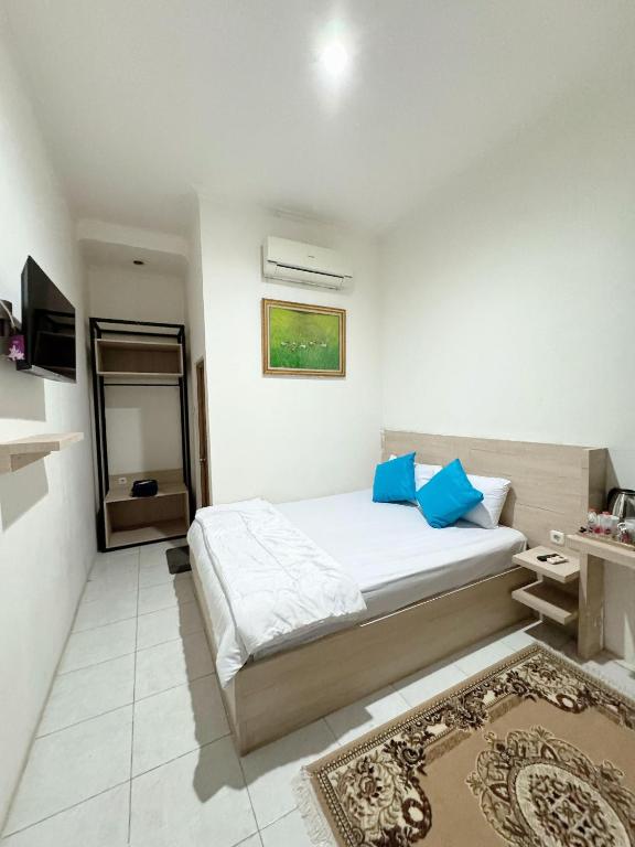 a bedroom with a bed with blue pillows and a tv at Hotel Rimadi in Jakarta