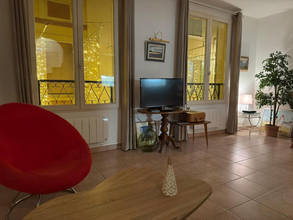 un salon avec une chaise rouge et une télévision dans l'établissement Sanary appartement 2-4 personnes à deux pas du port, à Sanary-sur-Mer