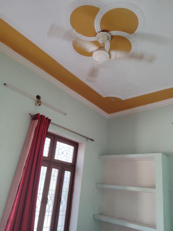 a ceiling fan in a room with a window at Chauhans house in Prayagraj