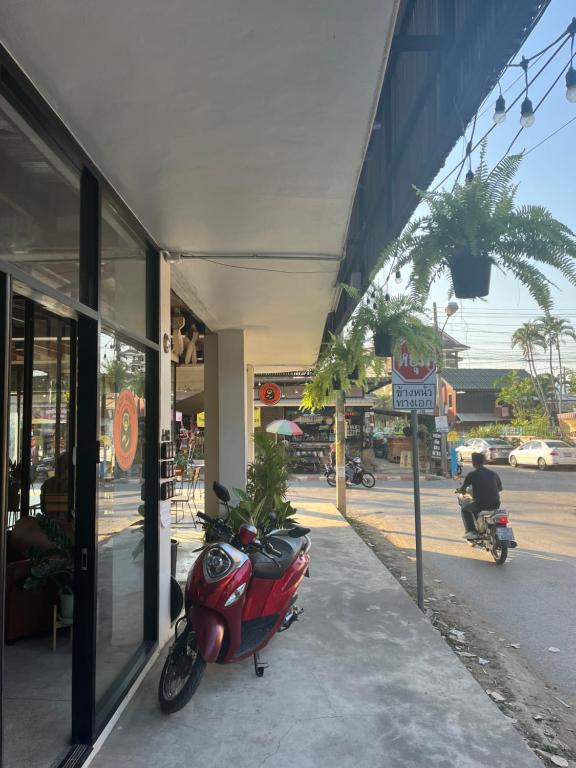 a red scooter parked on a sidewalk next to a building at Lazy Gibbon 2 Chiang Mai - Haiya in Chiang Mai