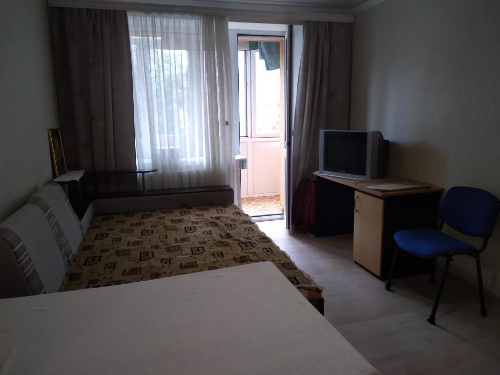 ein Schlafzimmer mit einem Bett, einem Schreibtisch und einem Fernseher in der Unterkunft Apartment - Panasa Myrnoho 20 in Myrhorod