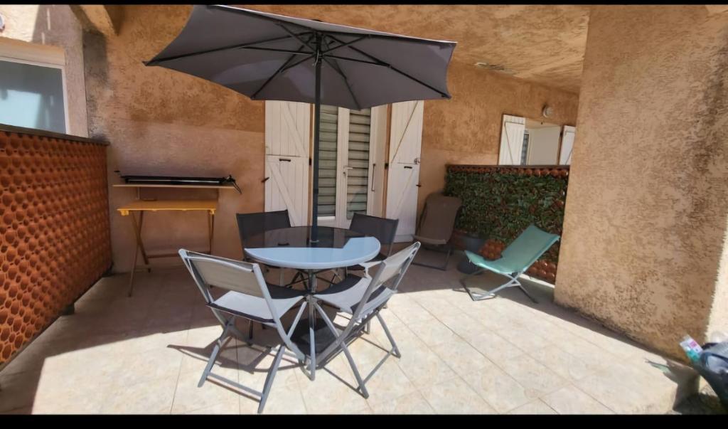 a table and chairs with an umbrella on a patio at L'Alizia in Sari Solenzara