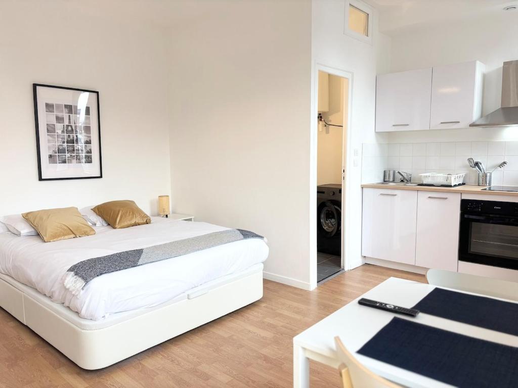 une chambre blanche avec un lit et une cuisine dans l'établissement Grand studio pour 2 voyageurs - Hypercentre, à Roubaix