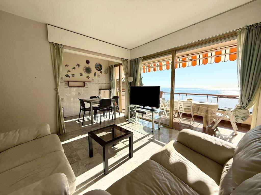 un salon avec un canapé, une télévision et une table dans l'établissement T3 lumineux terrasse vue mer, à Menton