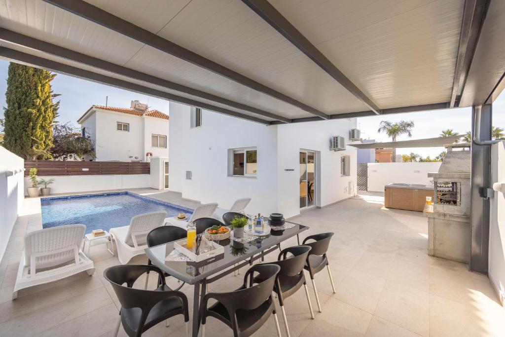 a patio with a table and chairs and a swimming pool at Villa Antonieta in Ayia Napa