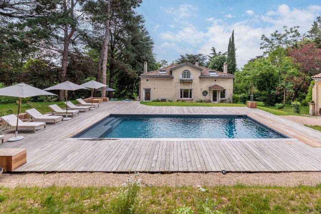 une piscine avec une terrasse en bois et une maison dans l'établissement La clarté - wonderful refurbish home with garden and pool, à Champagne-au-Mont-dʼOr
