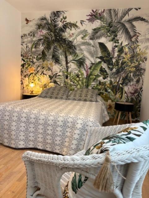 - une chambre avec un lit et un mur orné de plantes dans l'établissement Bienvenue à la maison !, à Vouillé