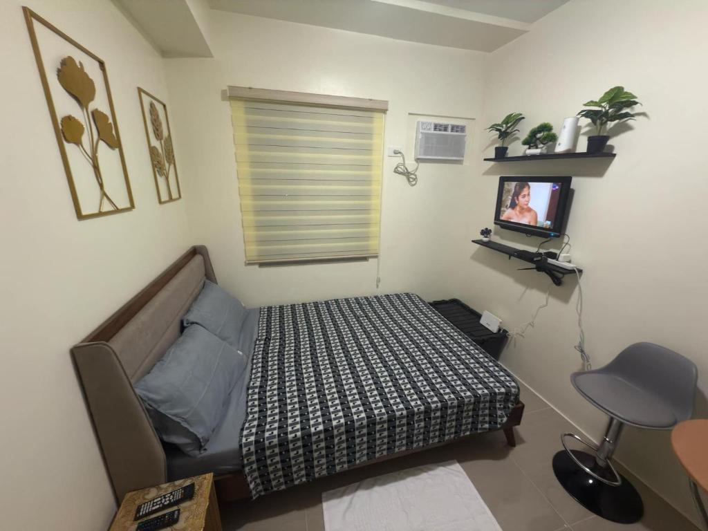 Un dormitorio con una cama y un televisor. en Condo in Cubao by Cindy, en Manila