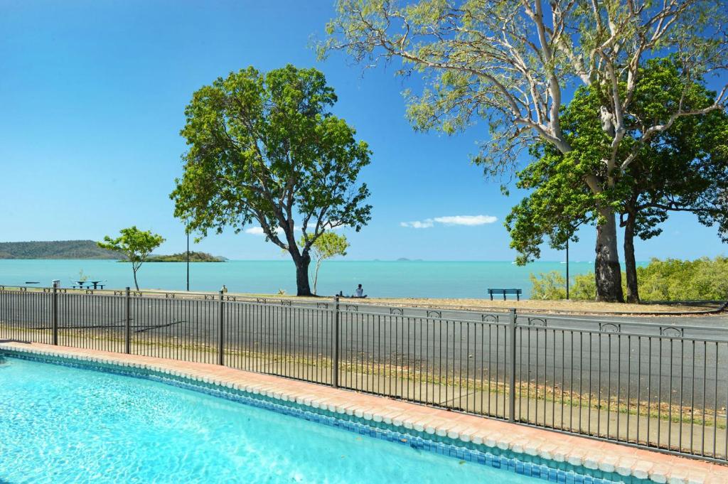 a swimming pool next to a fence and a beach at Whitsunday Waterfront Apartments in Airlie Beach