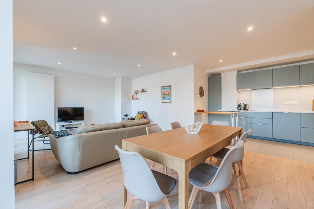 a kitchen and living room with a wooden table and chairs at L'Académie - Magnifique 3 chambres Krutenau avec parking in Strasbourg