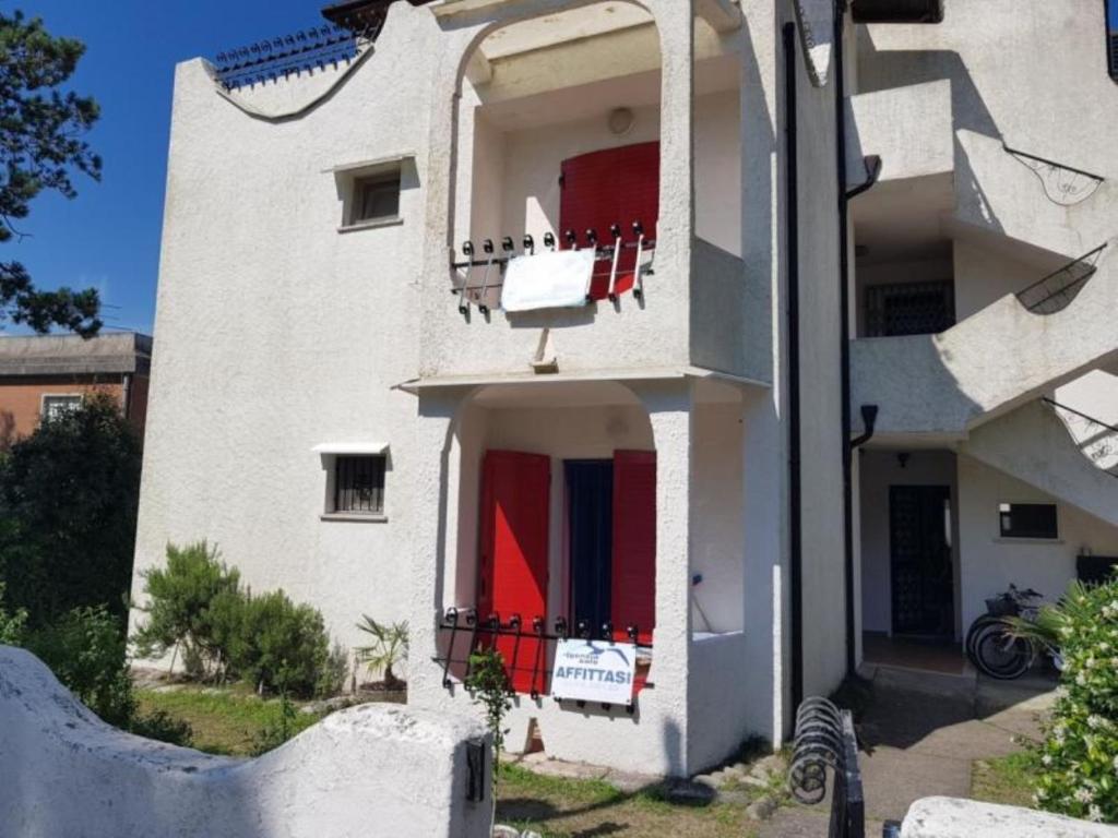 a white building with red doors and a balcony at Lara in Rosolina