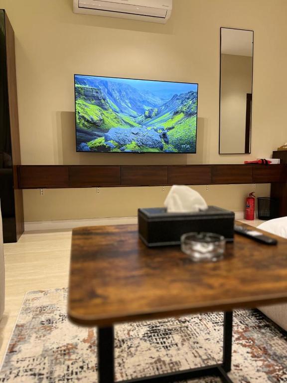 a living room with a table with a tv on the wall at Studio Sulimaniyah in Riyadh