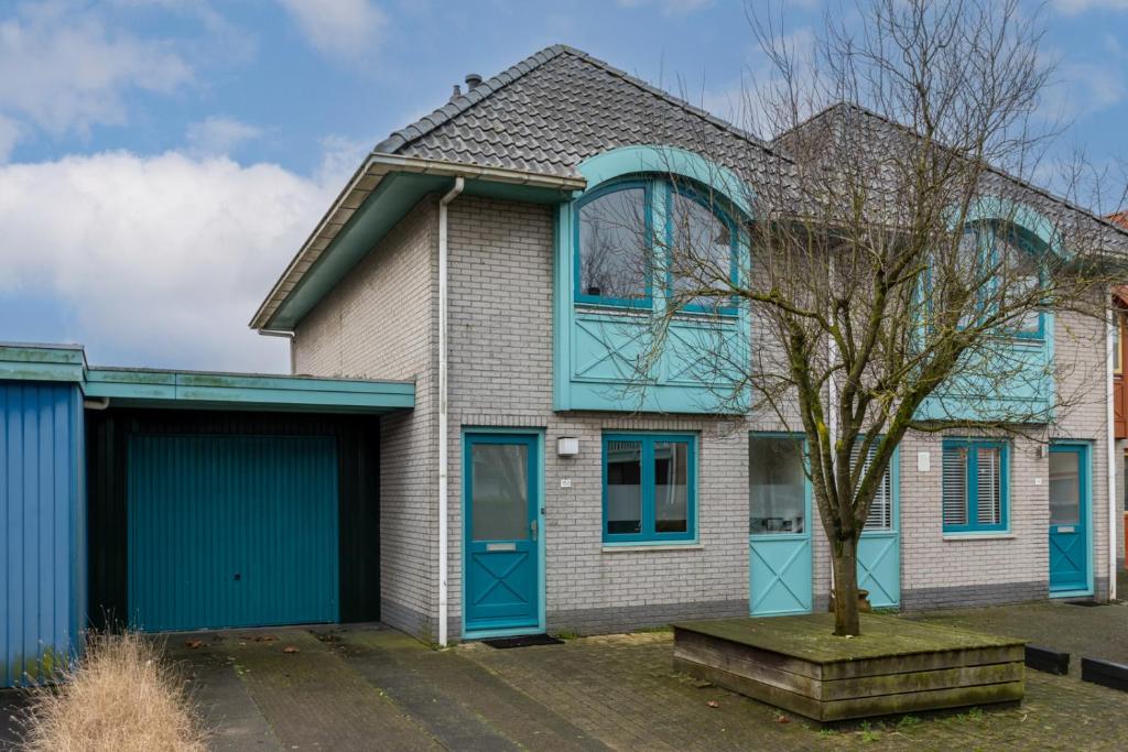 ein Haus mit blauen Türen und einem Baum in der Unterkunft Grasse 150 - Kustpark Village Scaldia in Hoofdplaat