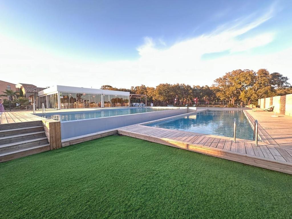 - une piscine avec de l'herbe verte à côté d'un bâtiment dans l'établissement Mini villa T3 de 48m2, à Lecci