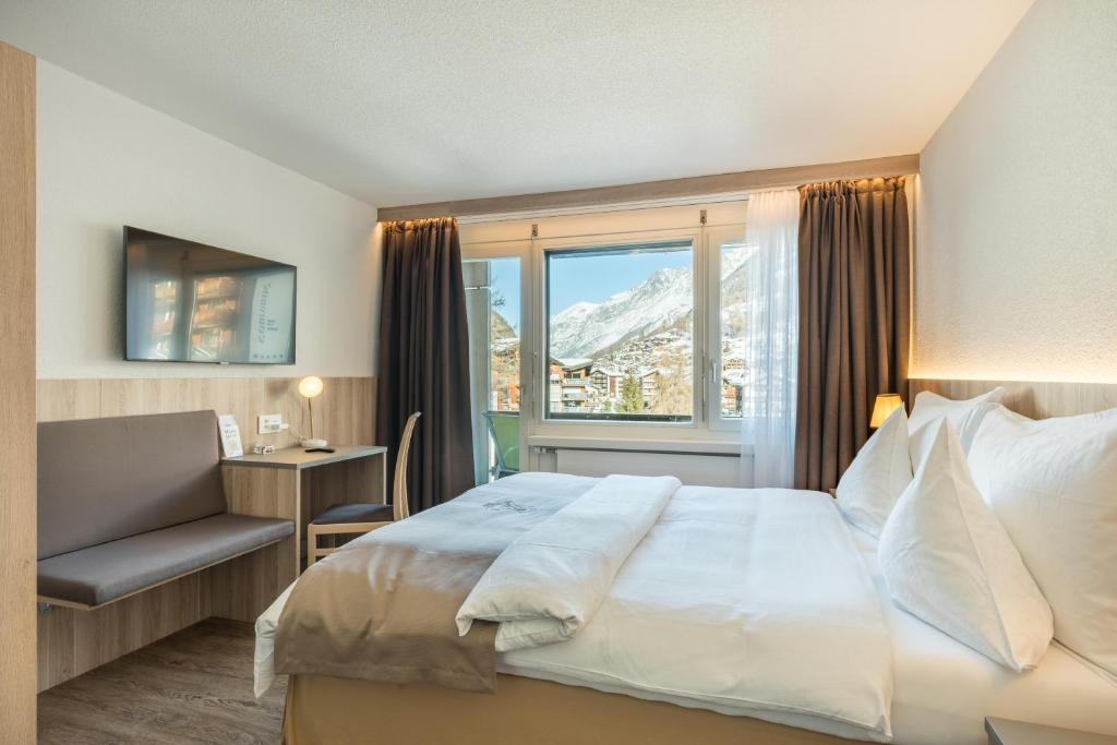 a hotel room with a bed and a window at Hotel Beau Rivage in Zermatt