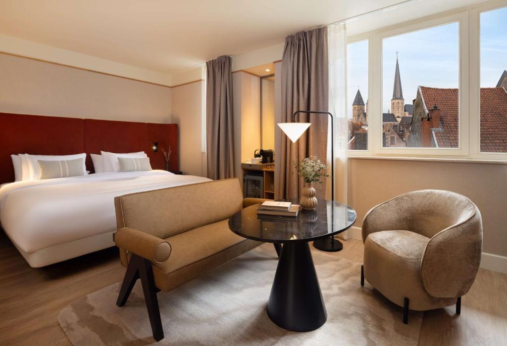 een hotelkamer met een bed, een stoel en een tafel bij NH Collection Gent in Gent