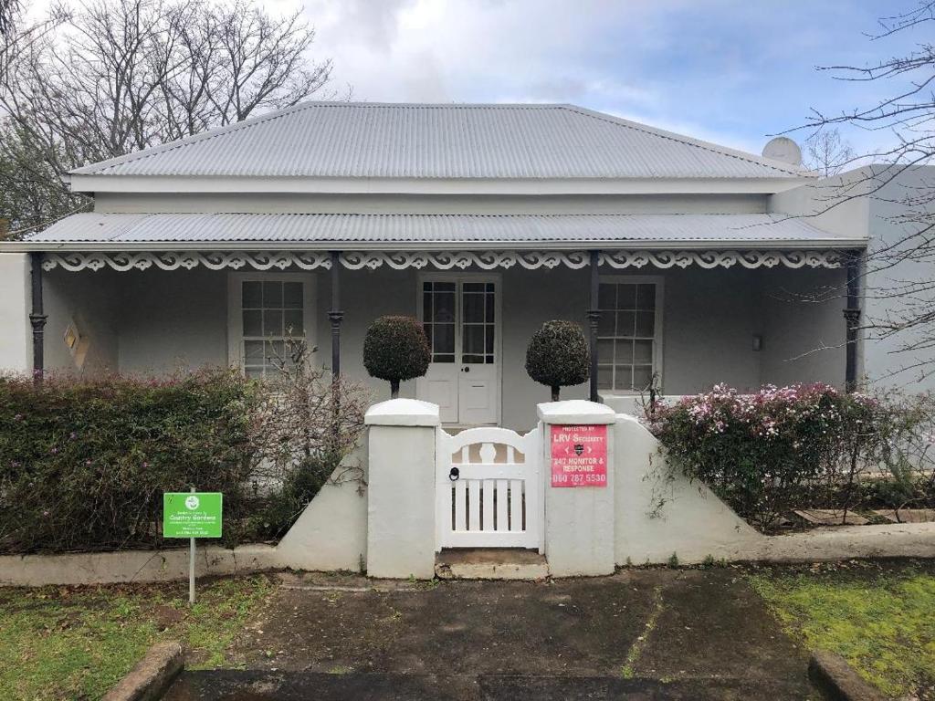 a white house with a gate in front of it at Charming Rose Cottage in Greyton