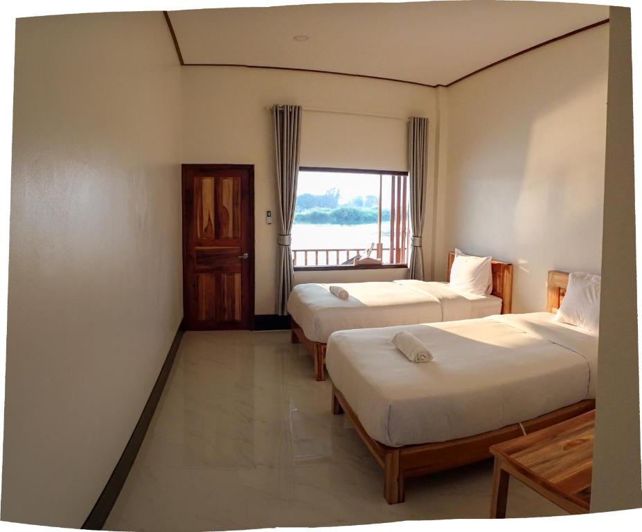 a room with two beds and a window at DODAND Studio & Sunset Riverside Guesthouse in Don Det