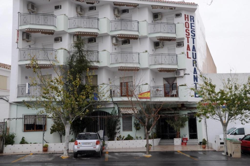 un edificio blanco con coches estacionados frente a él en Hostal Ruta Del Sur, en Huéscar