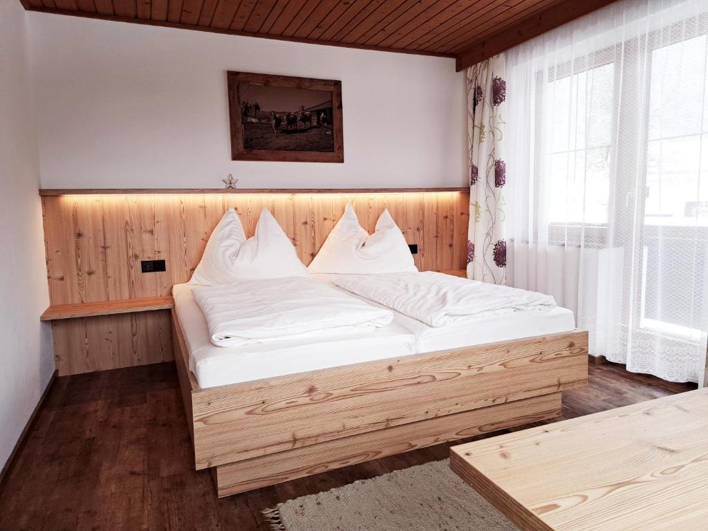 sypialnia z drewnianym łóżkiem z białą pościelą w obiekcie Bommerhof w mieście Waidring