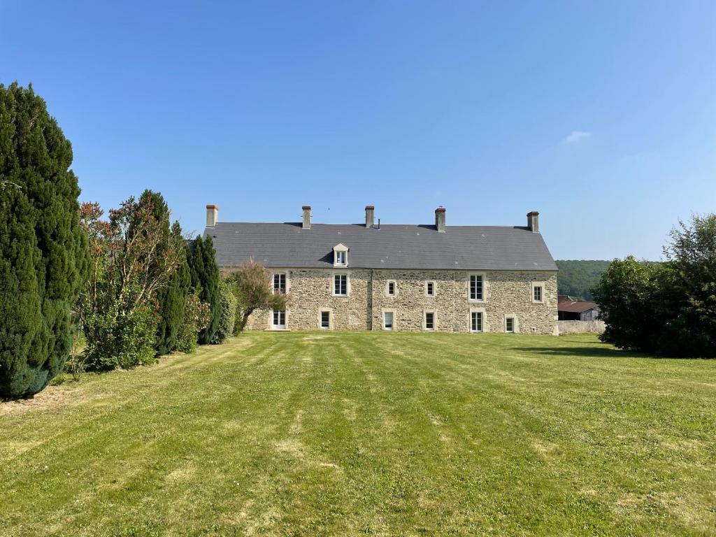 une ancienne maison en pierre avec une grande pelouse dans l'établissement Agréable maison de campagne, à Tournay-sur-Odon