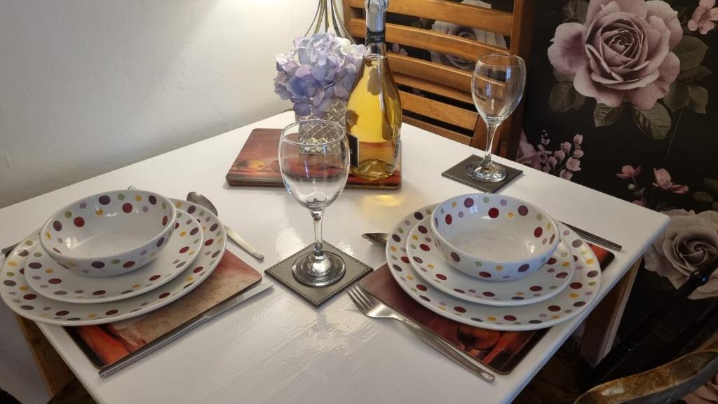 a table with two plates and glasses on a table at Haven Retreat at Hillrise in Herne Bay