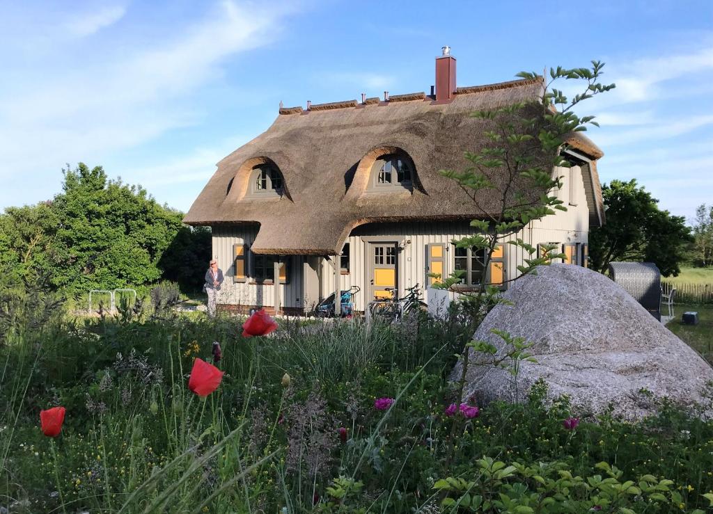 Ferienhaus Mein Ankerplatz 17 Feriendorf Klein Stresow Rügen by ruyastay في بوتبوس: منزل من القش مع حقل من الزهور