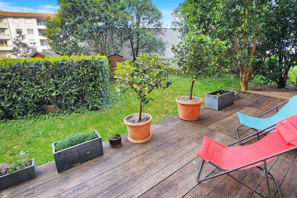 une terrasse en bois avec des plantes, une chaise et des arbres dans l'établissement Oasis Citadine, à Villeurbanne