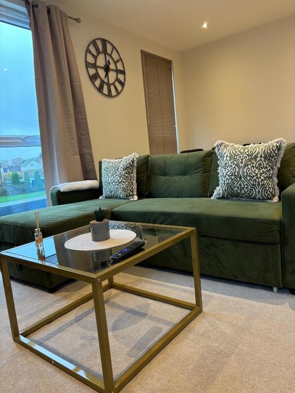 a living room with a green couch and a coffee table at 7 Thadan Apartments in Addlestone