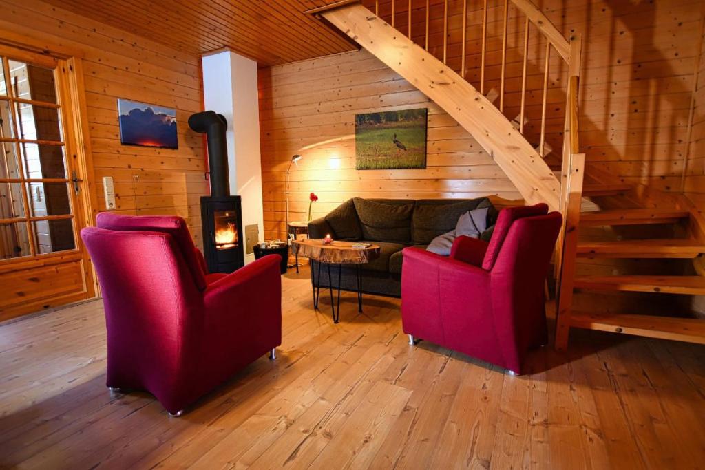 a living room with two red chairs and a staircase at Ferienhaus Blauvogel 4 in Hasselfelde