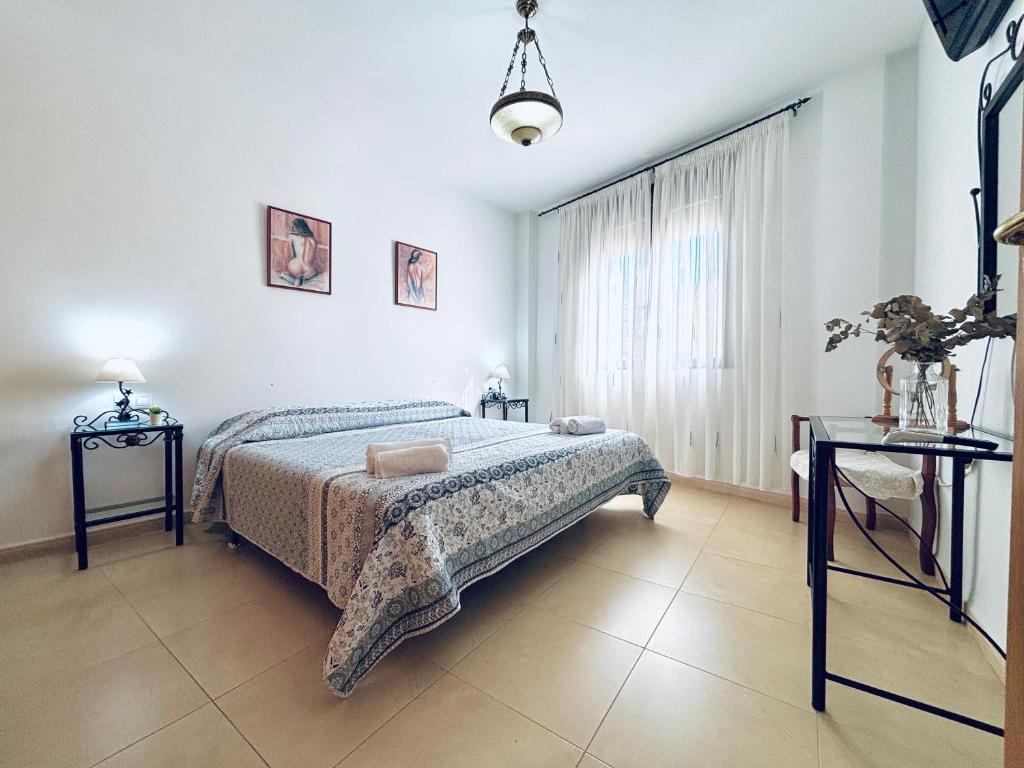 1 dormitorio con 1 cama, 2 mesas y una ventana en La Casa del Cuco, en Almodóvar del Río