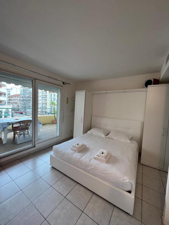 Cette chambre comprend un lit blanc et une grande fenêtre. dans l'établissement La Terrasse de Palais des Arts, à Nice