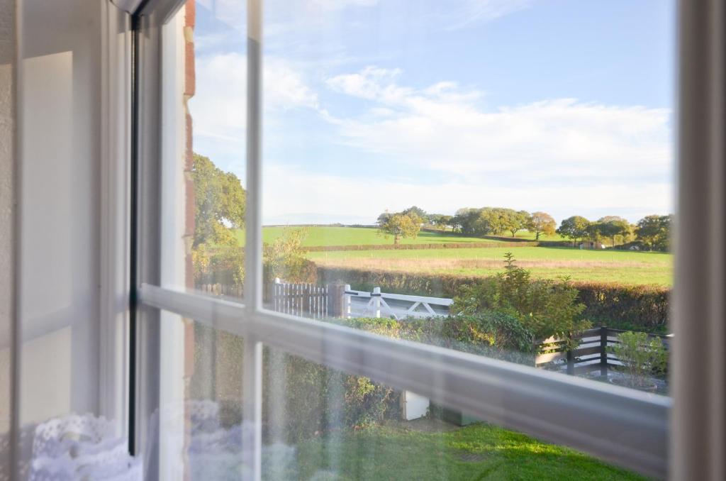 a window with a view of a field at Dassia-Rural Bungalow, Dog Friendly with Hot Tub Near Gurnard in Porchfield
