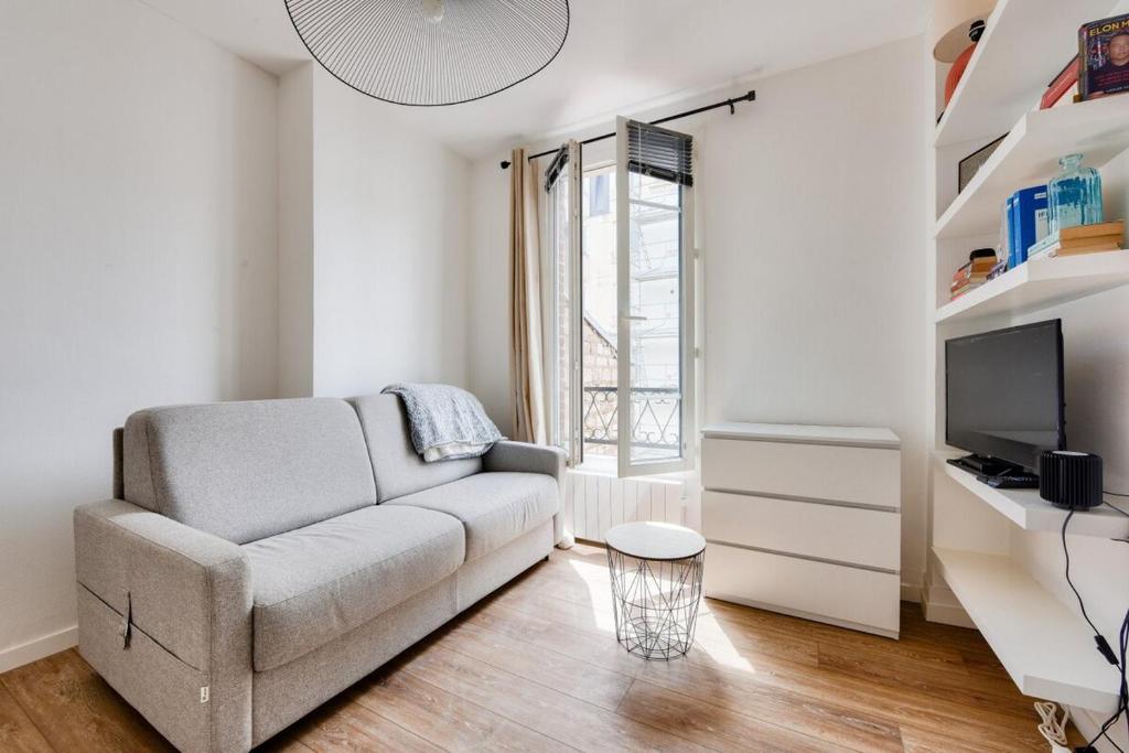 un salon avec un canapé et une télévision dans l'établissement Charming studio Paris Levallois Perret, à Levallois-Perret