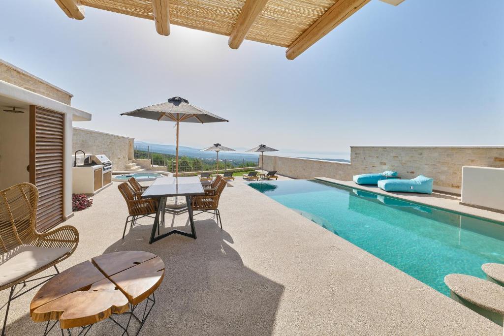 an outdoor patio with a table and chairs next to a swimming pool at Aegean Sunset Villas & Spa 'Villa Sun' in Skouloúfia