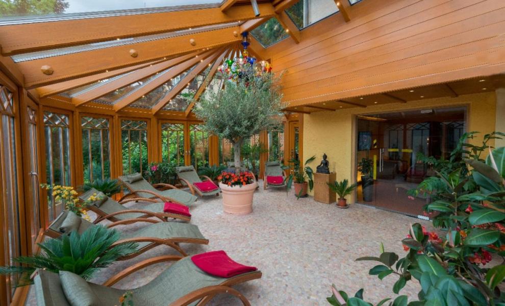 a conservatory with a bunch of chairs and plants at NaturMed Hotel am Park in Badenweiler