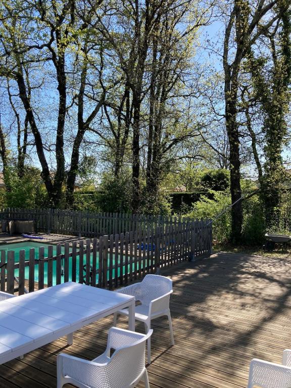 - une table de pique-nique et des chaises sur une terrasse avec une clôture dans l'établissement House with pool, à Quinsac