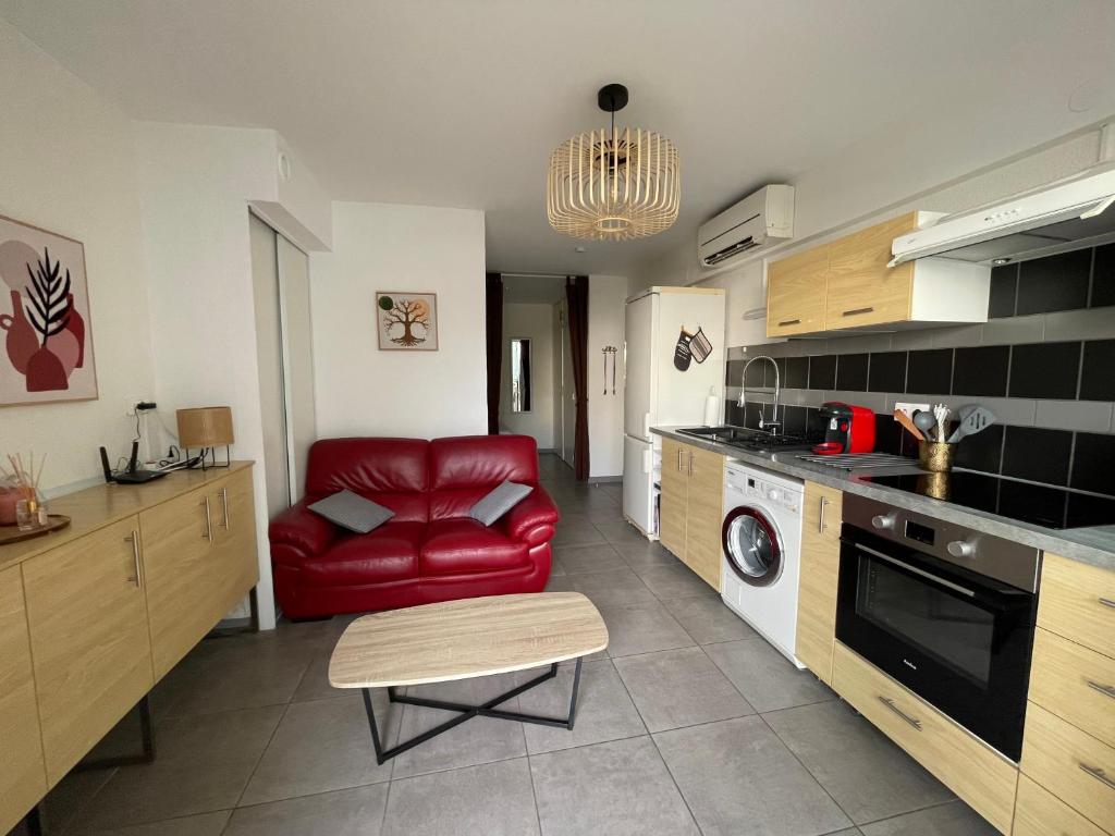 un salon avec un canapé rouge dans une cuisine dans l'établissement A deux pas des thermes et de l'étang de Thau, à Balaruc-les-Bains